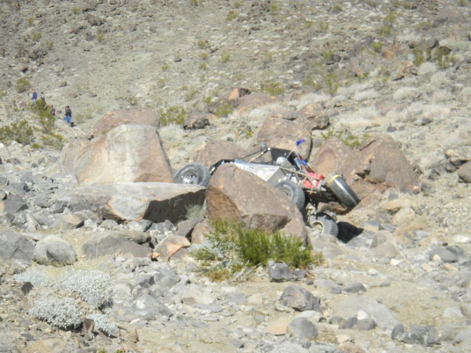 Off-road buggy wedged between large rocks on a rocky hillside