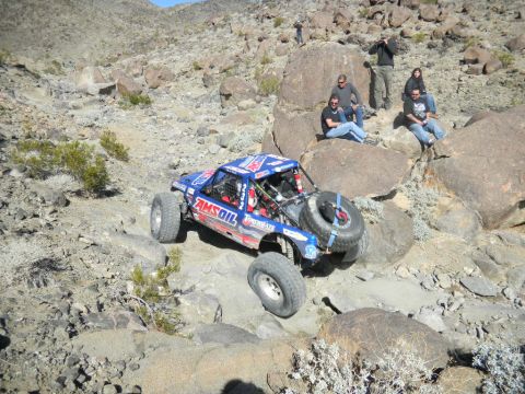 1997 Ford Ranger - Buggy with AMSOIL graphics tackles a challenging rocky course with spectators watching.