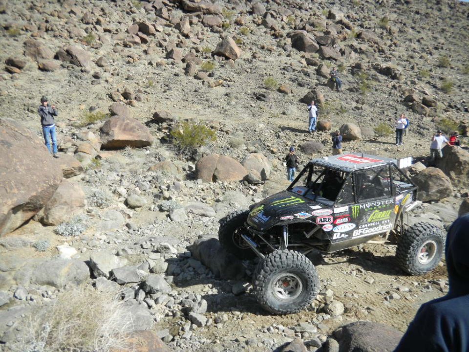 Off-road buggy with Monster Energy and BFGoodrich logos navigating a rocky desert terrain