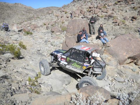 1997 Ford Ranger - A heavily modified off-road buggy tackles a challenging rocky course, with spectators watching from the side.