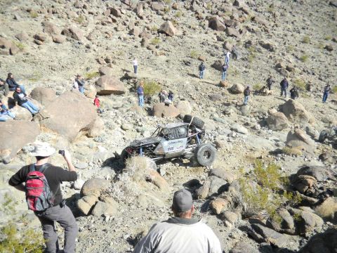 1997 Ford Ranger - A custom-built off-road buggy navigates a steep, rocky terrain with onlookers observing the race.