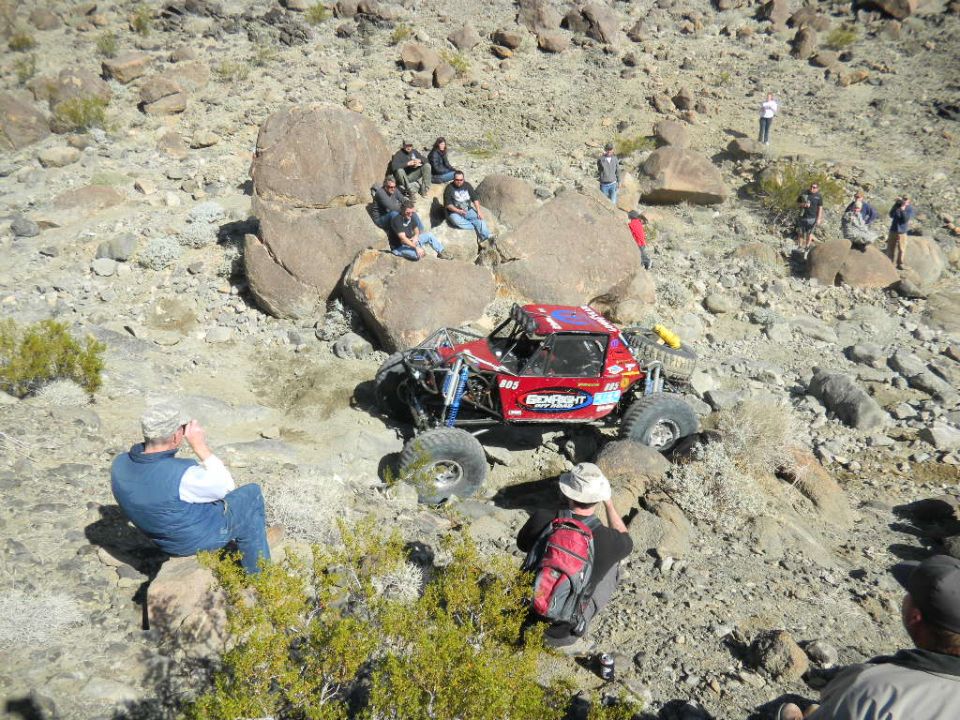 Red off-road buggy with large tires navigating a rocky desert terrain