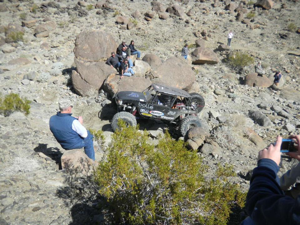 Off-road buggy climbing rocky terrain with spectators watching