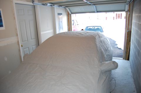2002 BMW M3 - A car is covered by a tarp in a garage, with another vehicle partially visible outside.