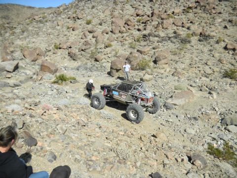 1997 Ford Ranger - A custom-built off-road buggy navigates a rocky desert landscape with spectators watching.