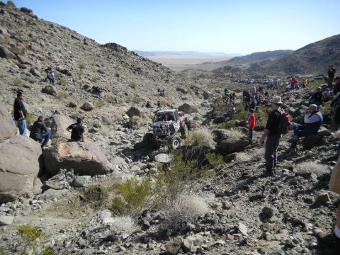 1997 Ford Ranger - Spectators watch an off-road buggy traverse a challenging rocky course in a desert landscape.
