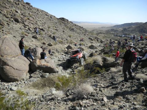 1997 Ford Ranger - Spectators watch an orange off-road vehicle navigate a challenging rocky terrain during an event.