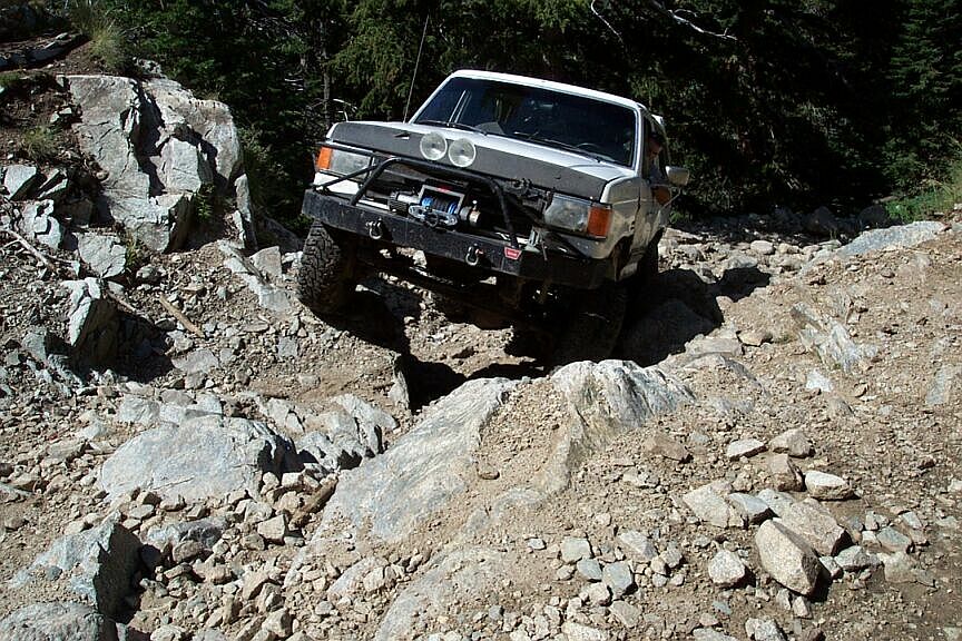 Lifted pickup with front winch crawling over rocks on a mountain trail