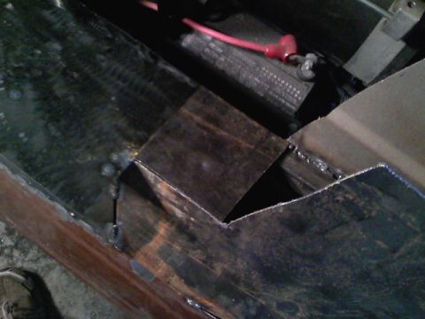 1990 Ford Bronco - A car battery with a red terminal cover is visible next to some newly welded metal components.