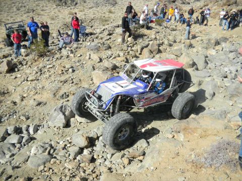 1997 Ford Ranger - A custom off-road buggy navigates a rocky terrain during a race event, with onlookers observing the action.
