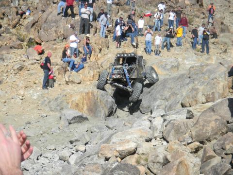 1997 Ford Ranger - An off-road buggy navigates a challenging rocky terrain during an event, observed by a crowd of onlookers.