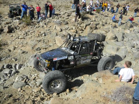 1997 Ford Ranger - A modified off-road buggy tackles a challenging rocky course with spectators watching.