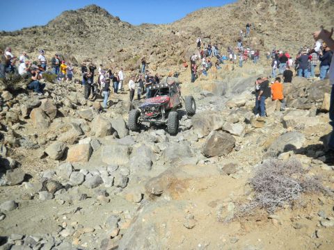 1997 Ford Ranger - A custom off-road buggy tackles a challenging rocky course during a race event, with spectators lining the hillsides.
