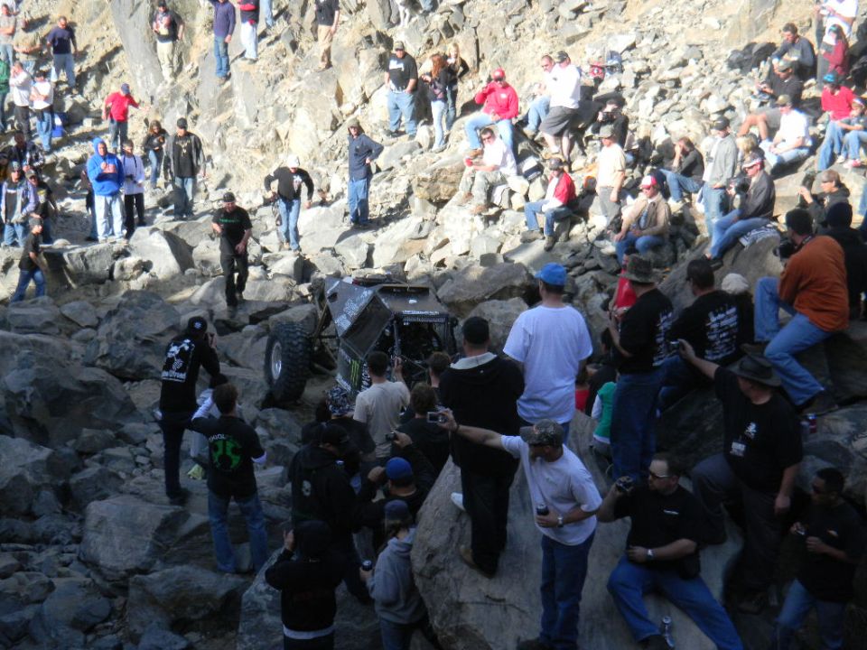 Off-road buggy stuck on rocks with spectators watching