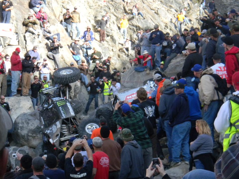 Off-road race truck stuck on rocks with spectators watching