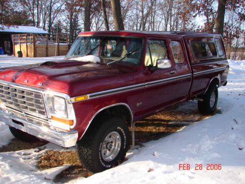 1979 Ford F-150 - This maroon 1979 Ford F-150 pickup truck, equipped with a camper shell, is parked in a snowy outdoor setting.