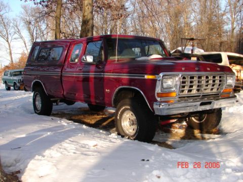 1979 Ford F-150 - Red 1979 Ford F-150 pickup truck with a camper shell sits in the snow, with another vehicle in the background.