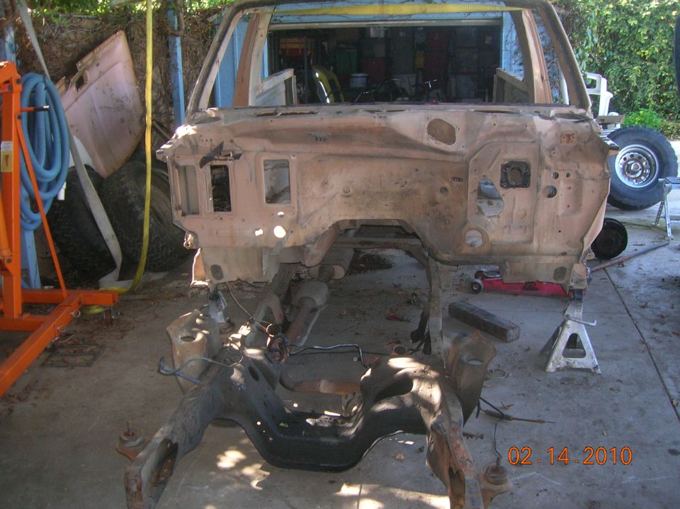 vehicle frame and firewall stripped down, on jack stands. Date stamp reads 02.14.2010