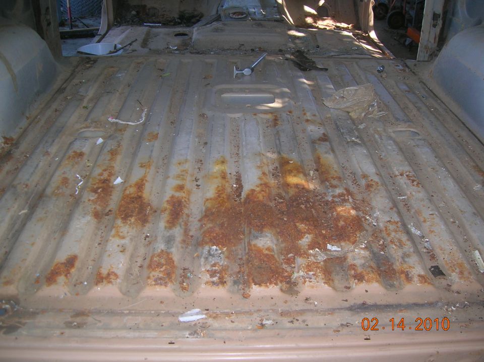 rusted floor of a vehicle interior, showing ribbed metal and debris