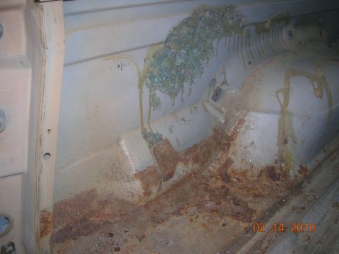 1985 Ford Bronco - The interior of a vehicle shows significant rust damage and some unknown debris on the paneling.