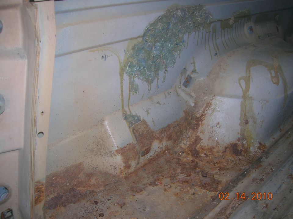 Interior of a vehicle showing rust on the floor and some green debris on the side panel. A date stamp reads 02/14/2010