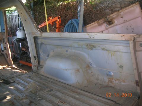 1985 Ford Bronco - The interior of a vehicle is shown disassembled, with visible rust and a portable engine hoist in the background.