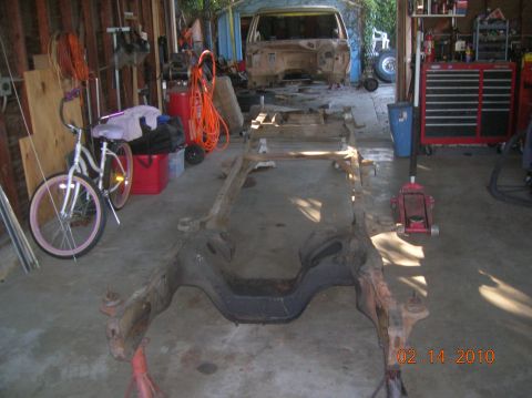 1985 Ford Bronco - A disassembled vehicle frame sits in a garage, awaiting restoration.