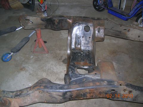 1985 Ford Bronco - Close-up of a heavily rusted vehicle frame section supported by jack stands.