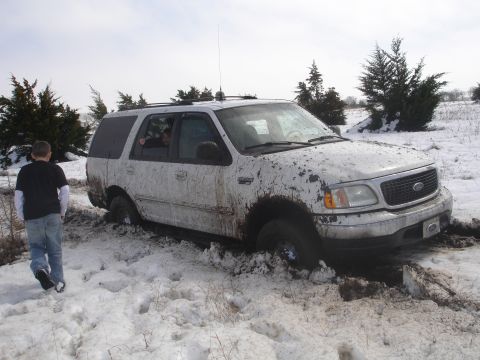 2002 Ford Expedition - A white 2002 Ford Expedition is stuck in snow and mud, with a person walking nearby.