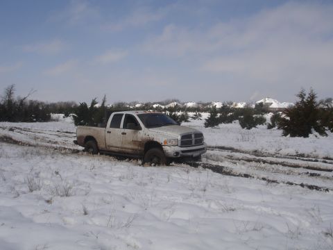 2002 Ford Expedition - White Dodge Ram pickup truck stuck in snow with tracks in the mud.