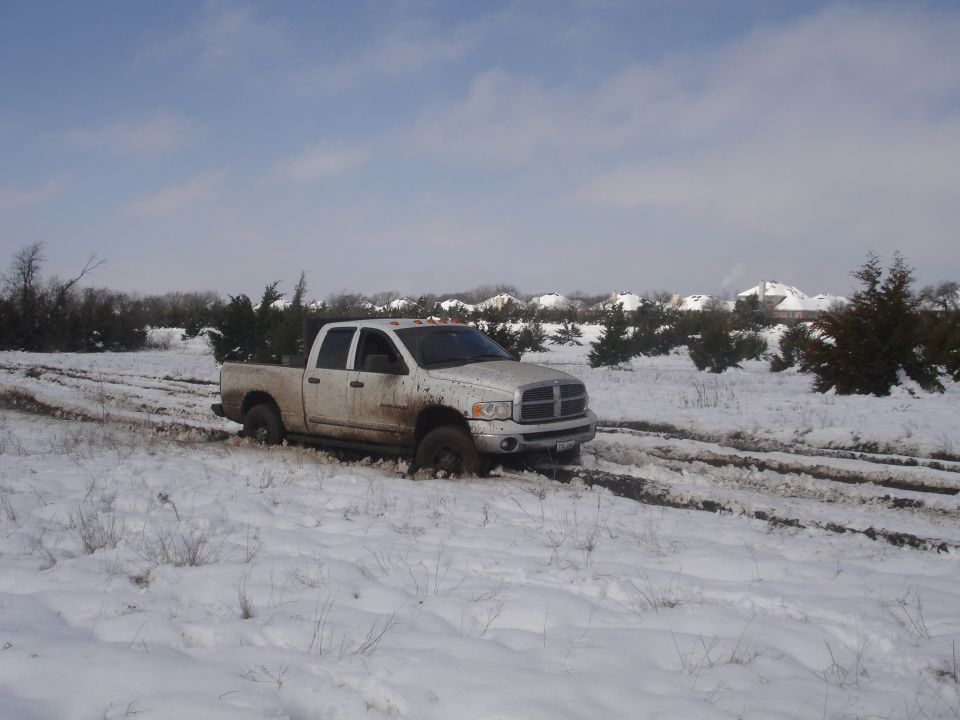 White Dodge Ram pickup truck stuck in snow, front 3/4 view