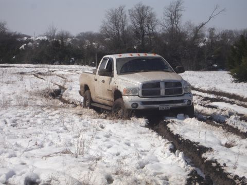 2002 Ford Expedition - This Dodge Ram pickup truck is stuck in the mud and snow, with tracks indicating it has been struggling to move.
