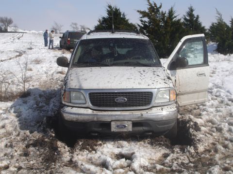 2002 Ford Expedition - White 2002 Ford Expedition stuck in snow and mud with front door open; another SUV visible in background.