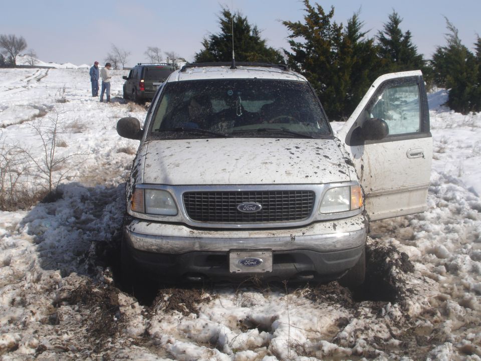 2002 Ford Expedition stuck in snow with front door open; another SUV behind it
