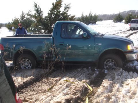 2002 Ford Expedition - A green Ford F-150 is stuck in the snow, with a second vehicle in the background.
