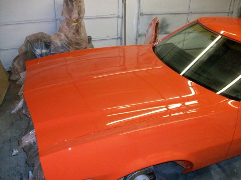 1973 Ford Ranchero - The bright orange paint on the hood and fender of a 1973 Ford Ranchero reflects overhead lights.