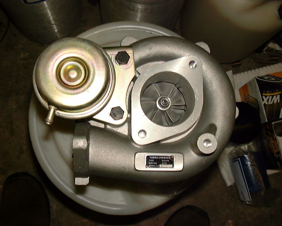 Nissan GT20 turbocharger with gold wastegate actuator, ID plate visible, on a bucket