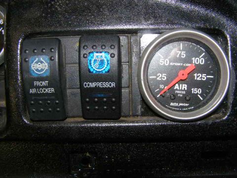 1993 Ford Bronco - Interior view of dashboard switches and an air pressure gauge.