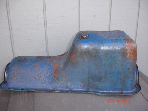 1978 Ford Mustang II - A blue oil pan with visible rust and a bolt on its upper surface sits on a gray surface.