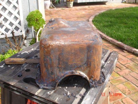 1978 Ford Mustang II - A heavily corroded oil pan sits on a workbench, awaiting restoration.