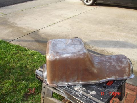 1978 Ford Mustang II - A rusty oil pan sits on a sawhorse outdoors, with a car tire visible in the background.