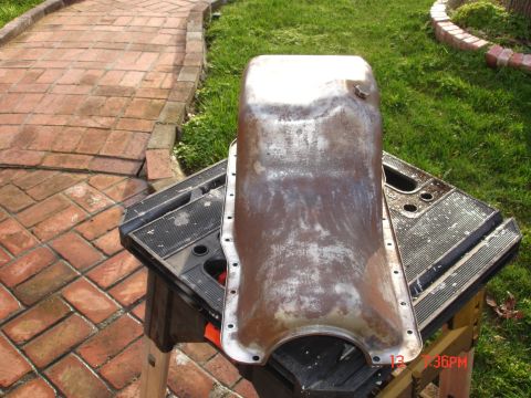 1978 Ford Mustang II - A metal oil pan sits on a black workbench, with a brick path and grass in the background.