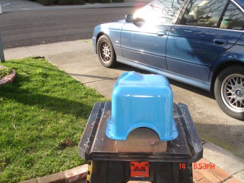1978 Ford Mustang II - A light blue car part sits on a workbench next to a blue sedan.