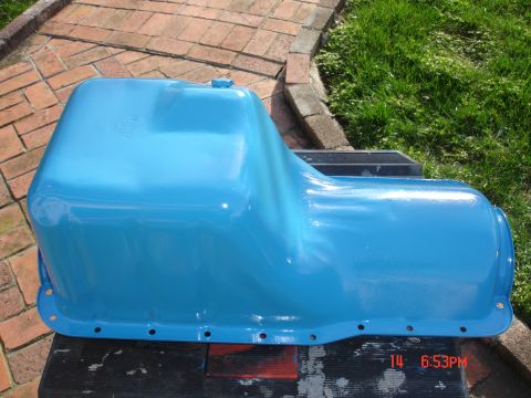 1978 Ford Mustang II - A blue painted oil pan sits on a black surface with brick and grass in the background.