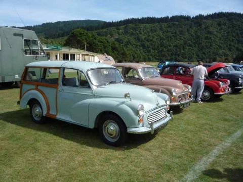 1969 MINI Cooper - A light blue station wagon with wood paneling is parked on a grassy field with other cars.
