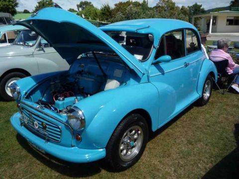 1969 MINI Cooper - A bright blue classic car is displayed with its hood open, parked on a grassy area next to another vehicle.