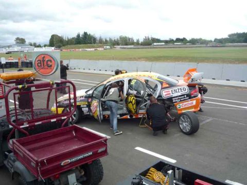 1969 MINI Cooper - Pit crew attends to a race car with sponsor decals on the track.
