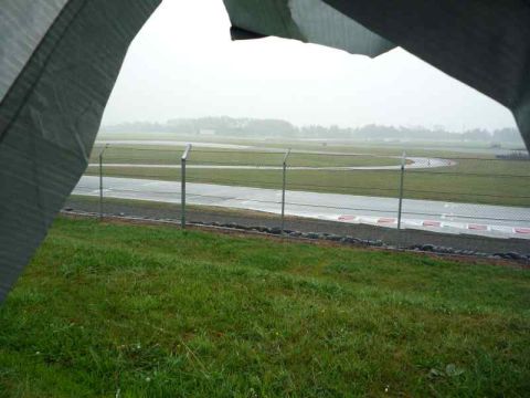 1969 MINI Cooper - A racetrack is visible through a tarp during a rainy day.