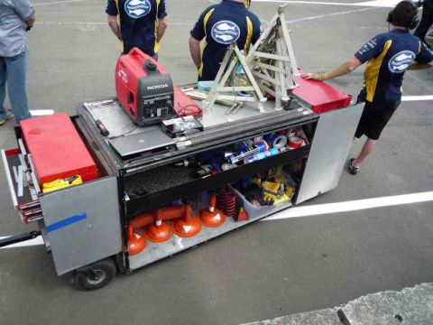 1969 MINI Cooper - A mobile tool cart is loaded with equipment, including a generator and suction cups, on a paved surface.