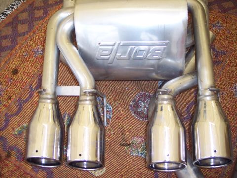 2006 Chevrolet Corvette - This image shows a set of Borla exhaust mufflers with four polished chrome tips, placed on a decorative rug.